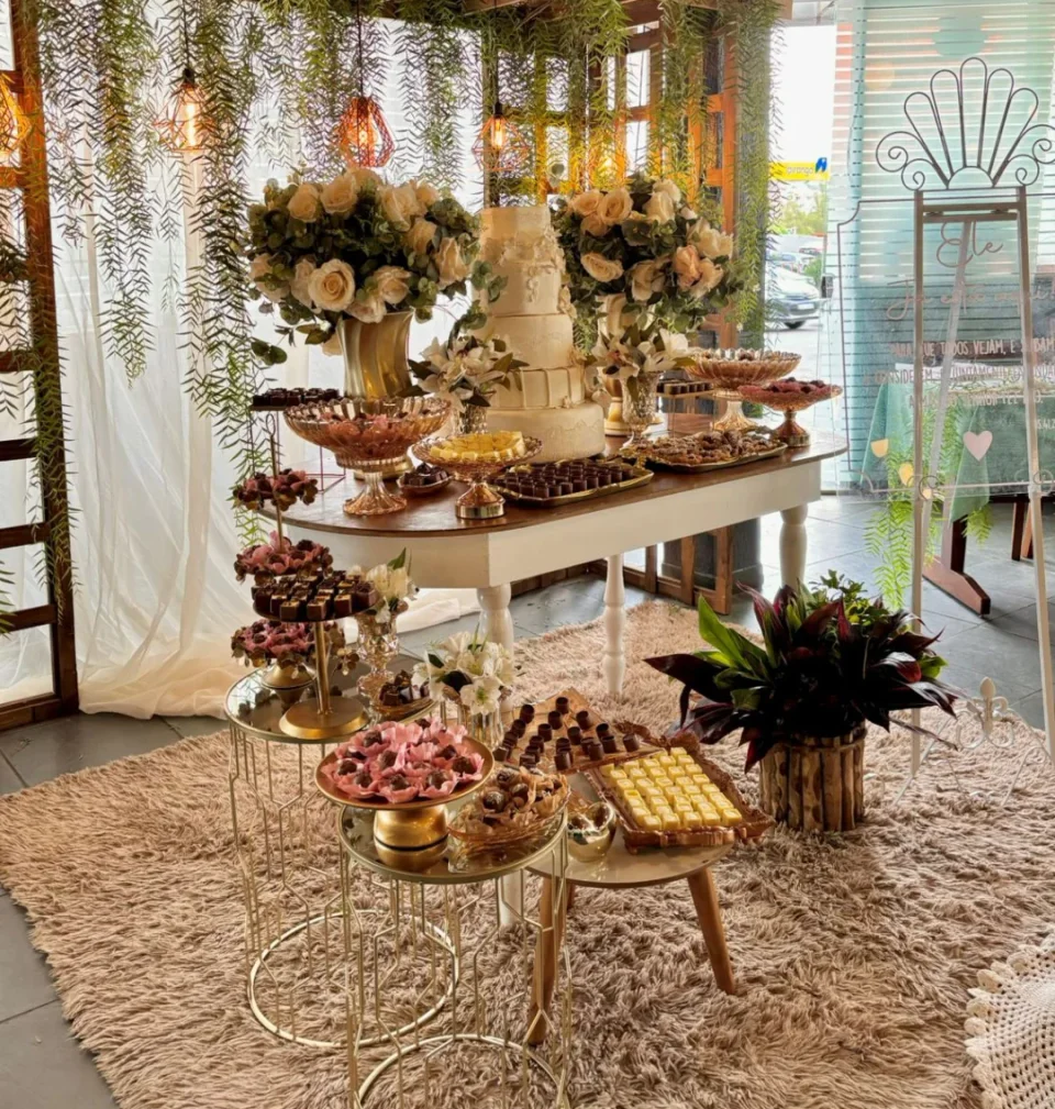 Mesa de doces e bolo decorada com flores e arranjos