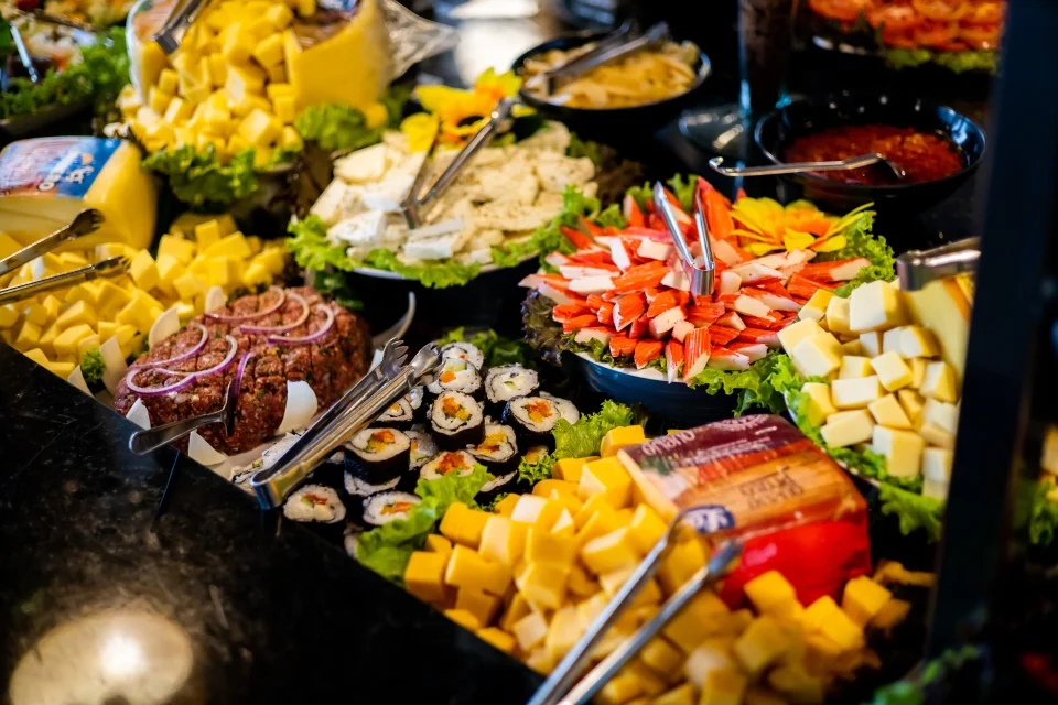 Vista do buffet livre com saladas, frios e pratos quentes lado a lado